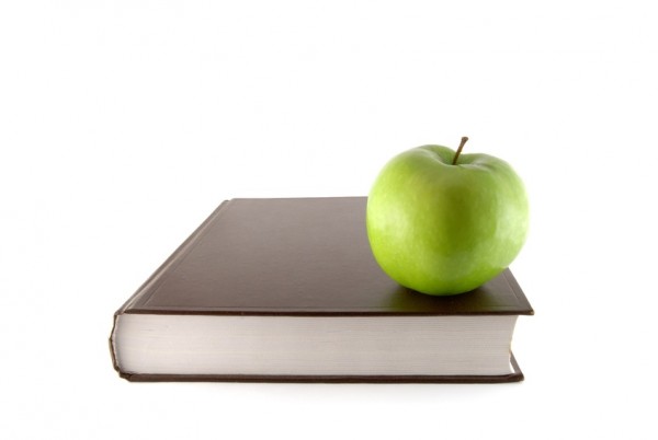 Book and green apple on the white background